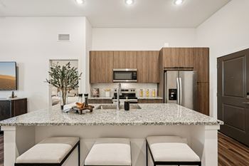 A modern kitchen with a granite countertop and stainless steel appliances